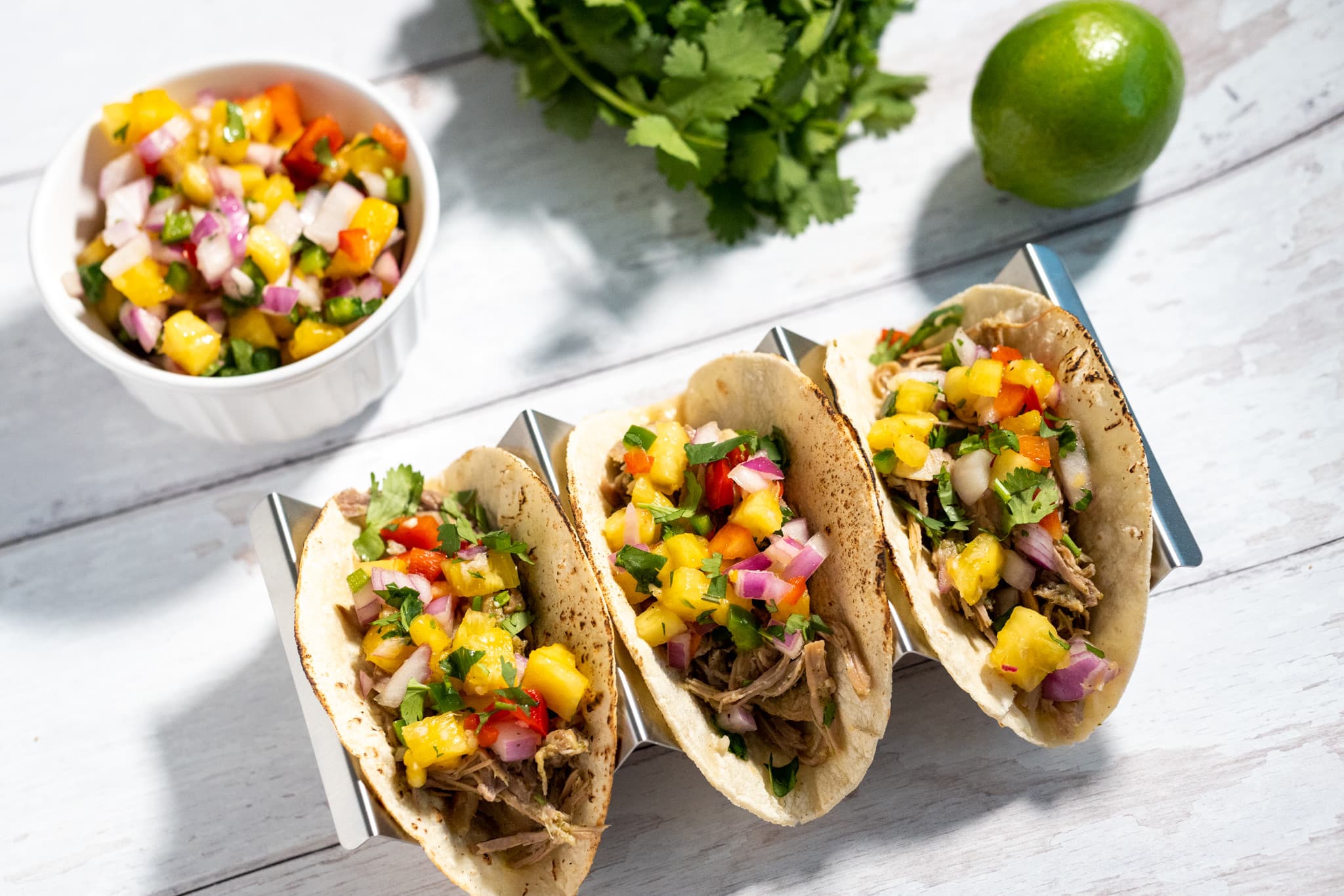 Mojo carnitas tacos topped with colorful pineapple salsa, cilantro and red onion